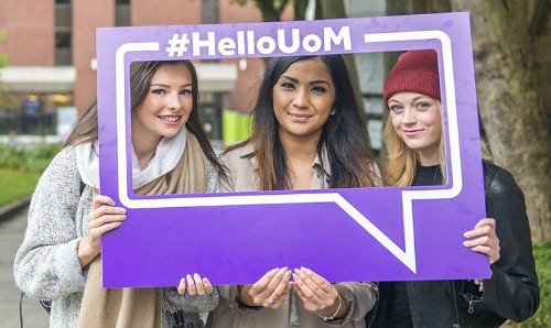 Current students holding Hello UOM sign to welcome new students