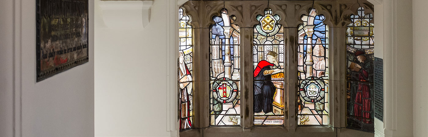 Stained glass window in Whitworth building showing Richard Copley Christie studying
