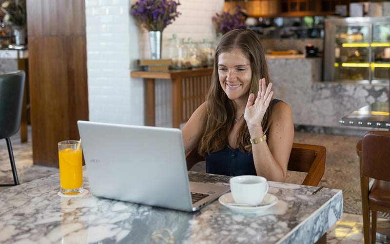 A woman waving at a laptop