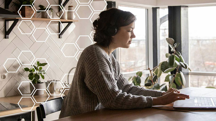 woman sat at a desk on her laptop with headphones on