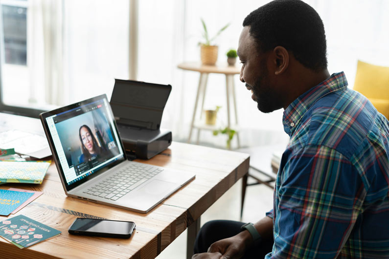 Man talking with a person over a video call on a laptop