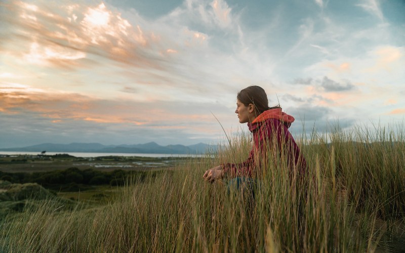 Student sat in grass by the coast