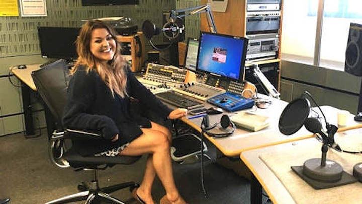 Young woman sitting at radio desk and smiling