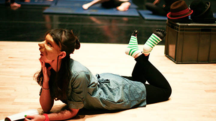 Young woman in theatrical mask lying on the floor pensively