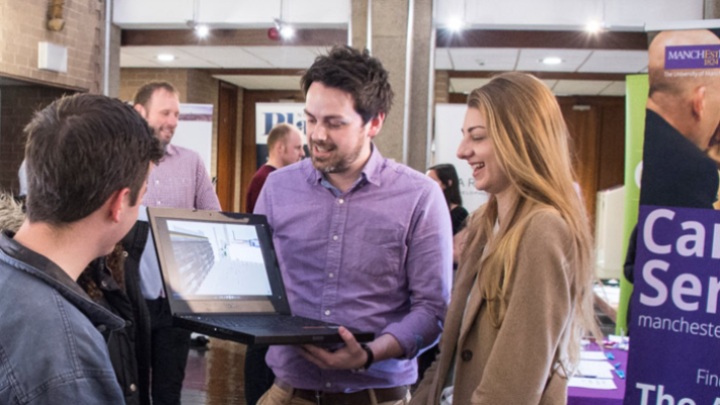 Woman and two men looking at laptop at an event