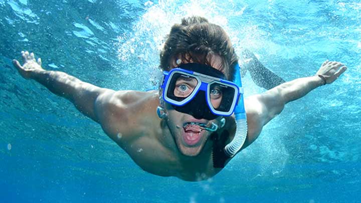 Male student swimming underwater in snorkelling wear