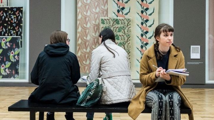 Students sat on bench in a gallery space