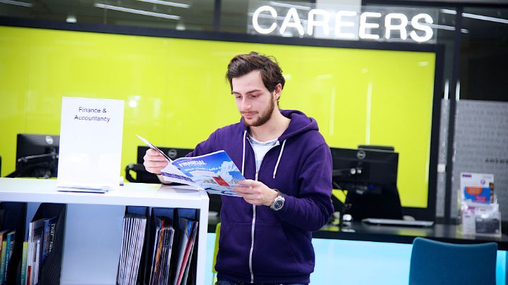 Male student reading magazine in Careers Service