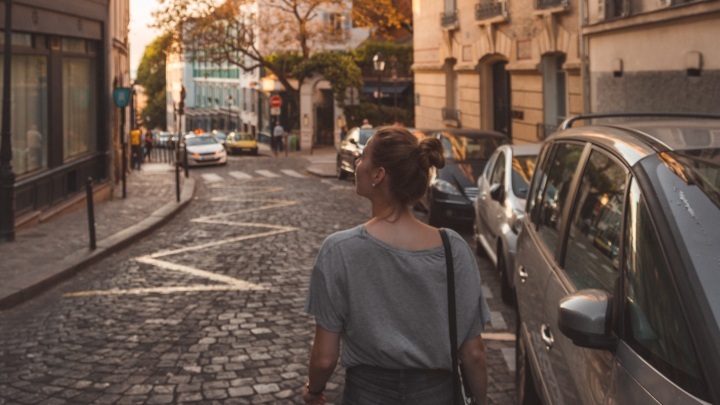 Woman facing away from camera, walking along a cobbled street