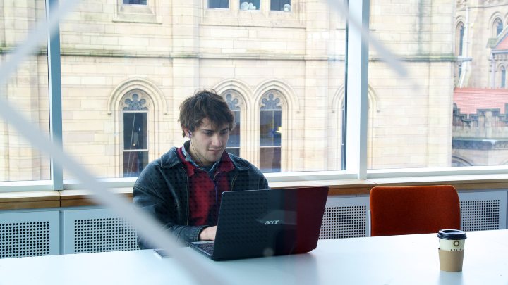 A male student working at a laptop