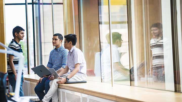 Three male students sat in the AMBS building