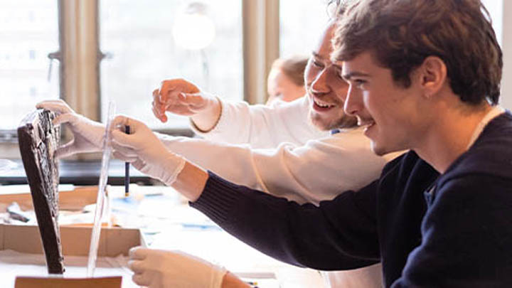 Two young men examining a Classical artefact