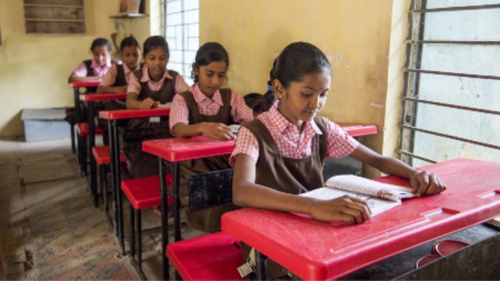 Five schoolgirls at at their desks.