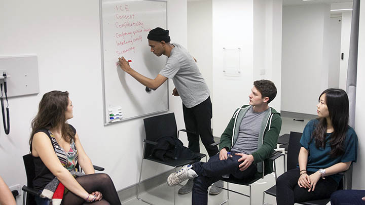 Medical students in a class making notes on a whiteboard.