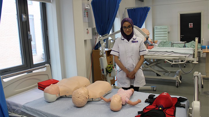 A nursing student with practice dummies.