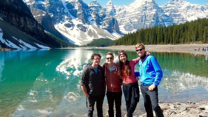A group of students stood in front of a lake and a mountain