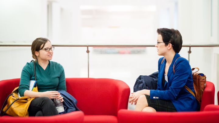 Two females sat on comfy chairs chatting