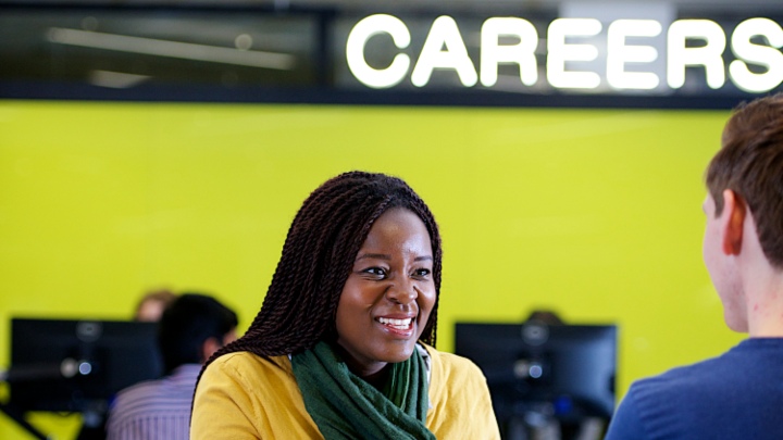 Smiling woman talking to man in front of neon careers sign.