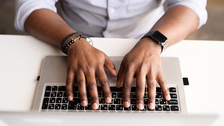 Hands typing on a laptop