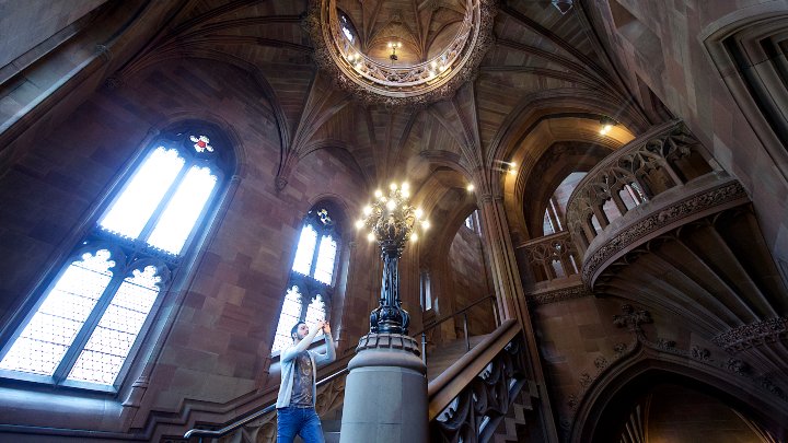 A student taking a picture of a ceiling in the John Rylands Library