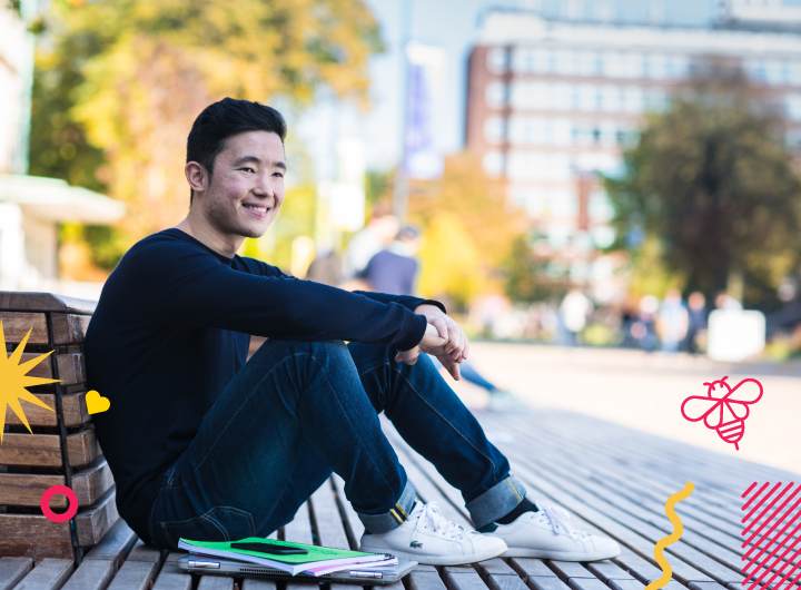 Male student kneeling down outside