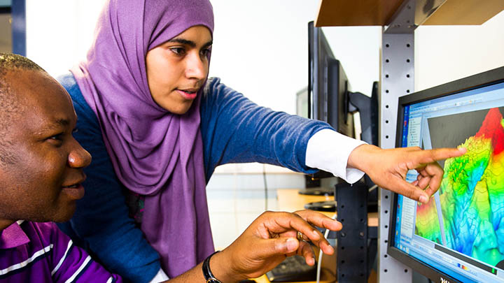 Students studying data on a computer screen.