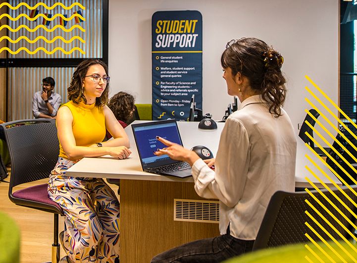 Female student speaking to woman at help desk 
