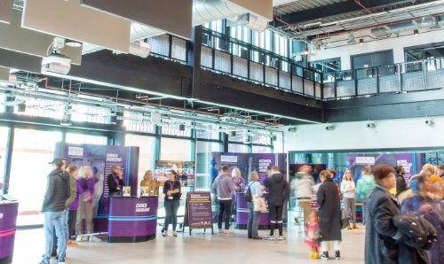 Recruitment fair with people speaking to staff on stands