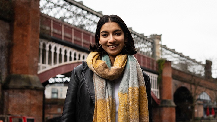 Smiling student standing by the canal