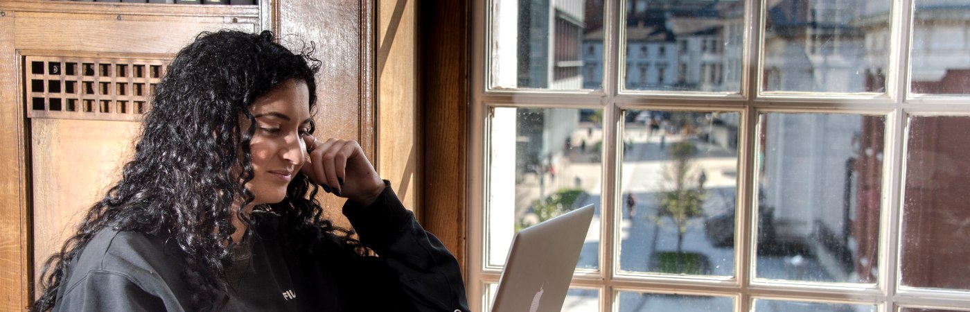 Female student using a laptop in the Main Library, The University of Manchester